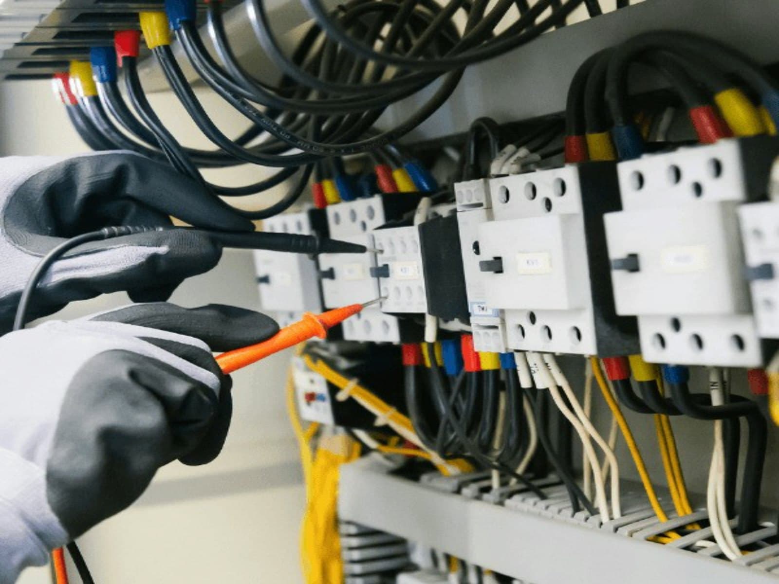 Elektrofachkraft prüft mit dem Multimeter einen Schaltschrank bei einer DGUV-V3-Prüfung